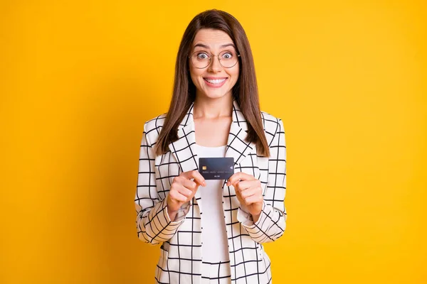 Foto retrato de la alegre mujer de negocios divertida mirando fijamente la celebración de la tarjeta bancaria de plástico aislado en el fondo de color amarillo vibrante —  Fotos de Stock
