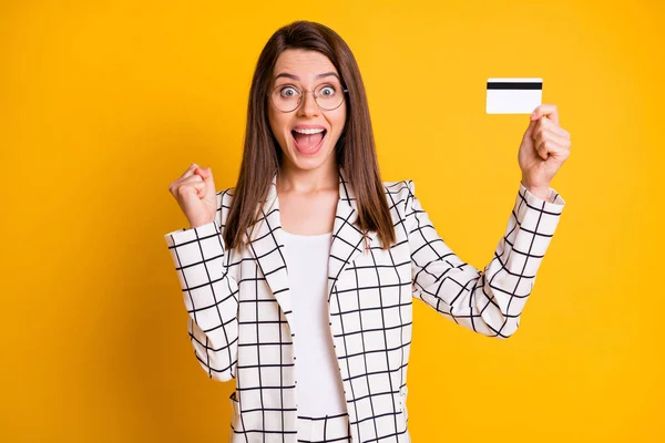 Retrato fotográfico de una mujer de negocios sorprendida que sigue mostrando la tarjeta de plástico del banco con traje a cuadros aislado sobre fondo de color amarillo brillante — Foto de Stock