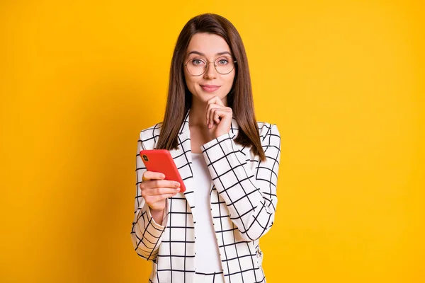 Фотопортрет умной деловой женщины, держащей сотовый телефон трогательным лицом в клетчатом костюме, изолированном на ярком желтом фоне — стоковое фото