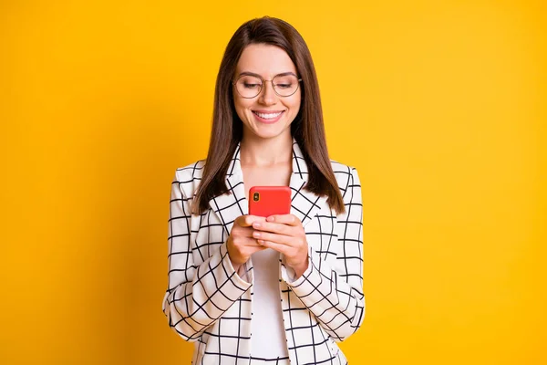 Foto av vackra attraktiva brunt hår student dam bära rutig jacka hålla händerna ser gadget isolerad gul färg bakgrund — Stockfoto