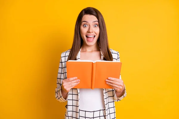 Foto von charmant überrascht Mädchen tragen karierten Blazer Lesen Copybook offenen Mund isoliert gelbe Farbe Hintergrund — Stockfoto