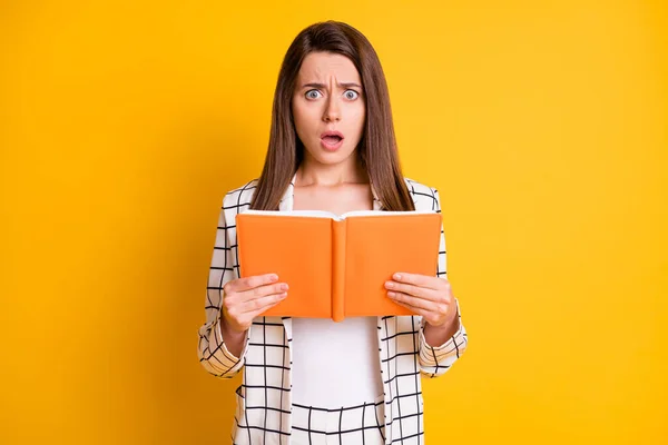 Φωτογραφία από ελκυστική έκπληκτη γυναίκα φορούν καρό ρούχα ανάγνωση βιβλίο τρομακτικό οικόπεδο ανοιχτό στόμα απομονωμένο κίτρινο χρώμα φόντο — Φωτογραφία Αρχείου