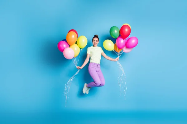 Longitud completa tamaño corporal foto de niña sosteniendo pila de globos de aire de colores saltando alto alegremente aislado sobre fondo de color azul vibrante — Foto de Stock