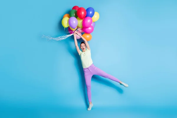 Foto de tamaño completo del cuerpo de la niña manteniendo globos de aire asombrado viento aislado sobre fondo de color azul vibrante — Foto de Stock