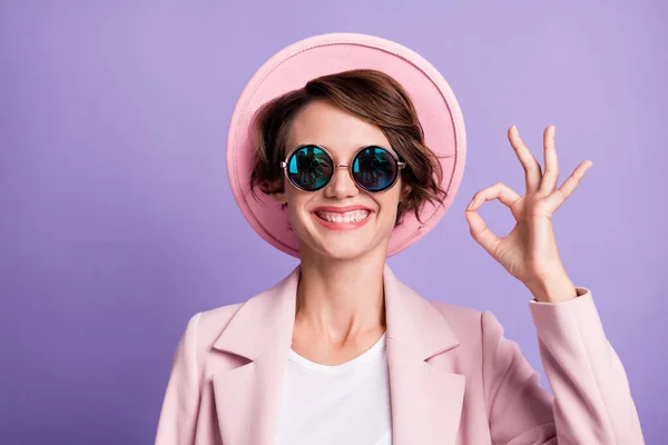 Fénykép a fogas sugárzó lány nő visel rózsaszín vintage felszerelés sapka szemüveg mutatja okey egy kézzel elszigetelt lila színű háttér — Stock Fotó