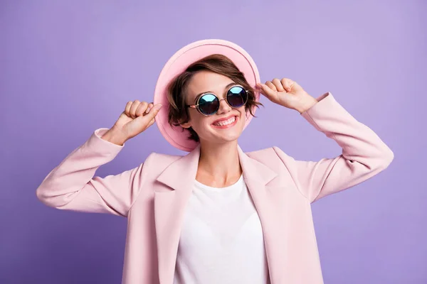 Foto av lockigt glad flicka kvinna bära rosa retro blazer mörka glasögon armhatt ser tomt utrymme isolerad violett färg bakgrund — Stockfoto