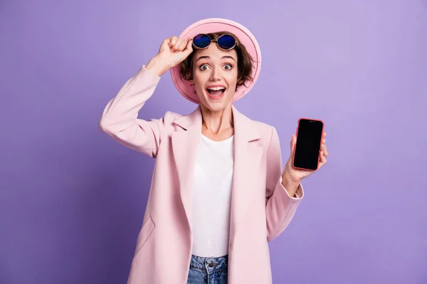 照片上的年轻女子穿着便帽夹克，手持电话与紫色背景的法律价格隔离 — 图库照片