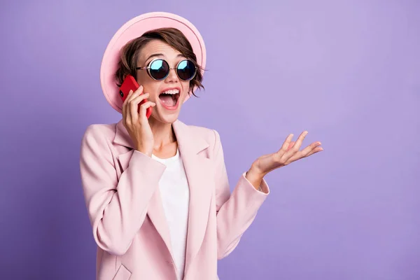 Foto de la joven joven muy emocionada hablando teléfono usar abrigo sombrero gafas espacio vacío aislado sobre fondo púrpura —  Fotos de Stock
