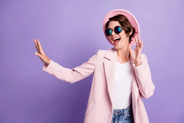 Foto di piuttosto ottimista giovane donna danza indossare cappotto cappello occhiali top look spazio vuoto isolato su sfondo di colore viola — Foto Stock