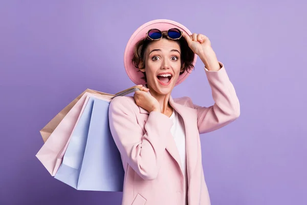 Portrait of crazy sweet bob hair young woman hold shoppers take off glasses wear pink cap coat isolated on purple color background