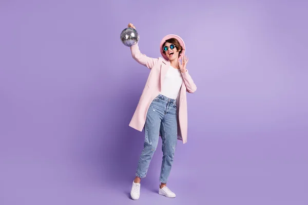 Фотографія повної довжини усміхненої здивованої молодої леді весело тримає в руці срібний м'яч ізольований фіолетовий кольоровий фон — стокове фото