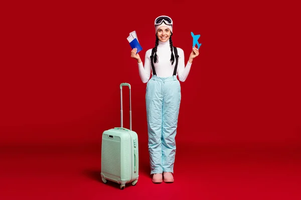 Fulll size photo of young happy girl with tails hold passport wear blue pants leaving for winter vacation isolated on red color background — Stock Photo, Image