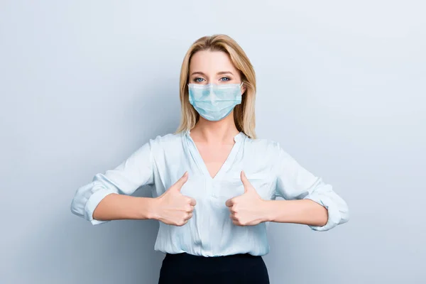 Retrato de mulher positiva mostrando dois polegares para cima usando máscara facial azul isolado em fundo cinza — Fotografia de Stock