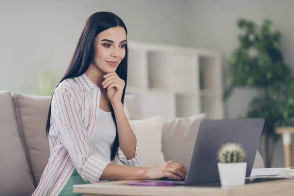 Photo de jolie jeune femme d'affaires assis confortable canapé main menton look ordinateur écran porter chemise dans le bureau à la maison à l'intérieur — Photo