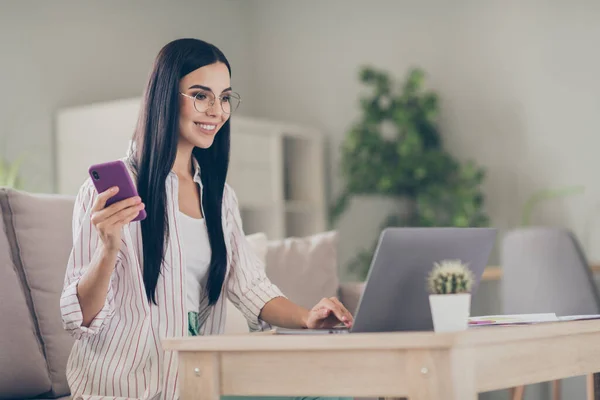 Foto av unga företag dam hålla telefon skriva netbook bära glasögon skjorta i hemmet arbetsstation inomhus — Stockfoto