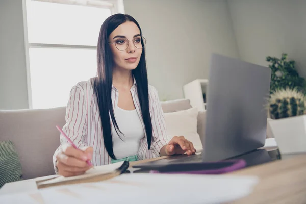 Foto de joven mujer de negocios sentarse sofá sostener lápiz escribir diario palma mensajes de texto usar gafas camisa en el hogar estación de trabajo en interiores — Foto de Stock