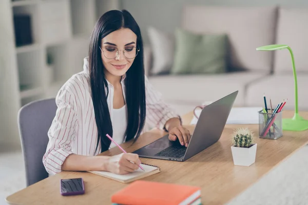 Retrato fotográfico del trabajo concentrado reflexivo de la mujer casera del negocio que toma notas con la pluma en el planificador que hace el proyecto — Foto de Stock