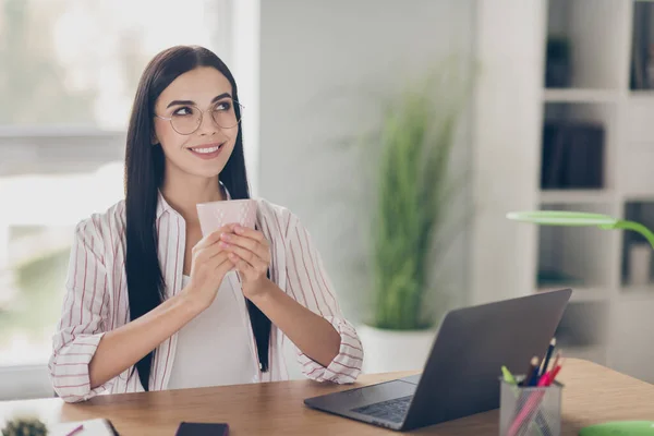 Photo de femme intelligente comptable assis table portant des lunettes ayant le repos tenant les bras de la tasse regardant espace vide poste de travail intérieur — Photo