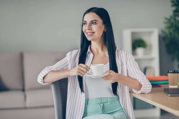 Foto van vrolijke glimlachende vrouw makelaar zitten stoel drinken thee op zoek naar lege ruimte indoor werkstation — Stockfoto