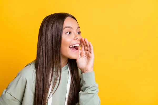 Fénykép trükkös vicces iskolás lány viselni alkalmi szürke ruhát kar száj mondani titkos elszigetelt sárga szín háttér — Stock Fotó