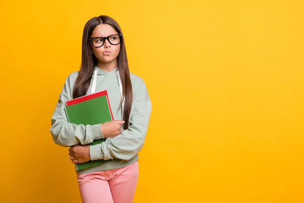 Foto da menina da escola profundo pensativo olhando espaço vazio manter livro casual isolado no fundo de cor amarela — Fotografia de Stock