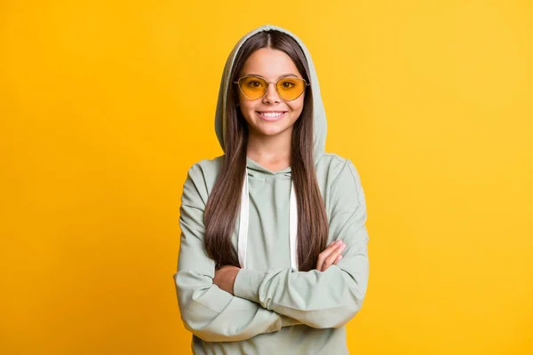 Retrato de la alegre niña de la escuela brazos cruzados usar gafas de sol ropa verde claro aislado en el fondo de color amarillo —  Fotos de Stock