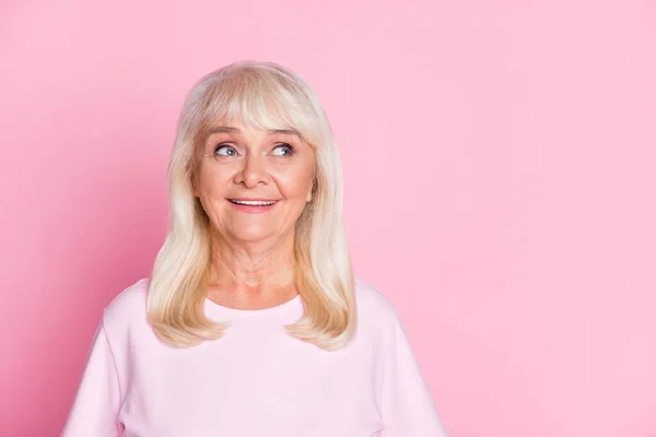 Foto porträtt av nyfikna leende mormor blont hår tittar på tomt utrymme bär casual outfit isolerad på pastell rosa färg bakgrund — Stockfoto