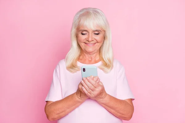 Foto ritratto di carino nonna utilizzando smartphone navigazione internet sorridente isolato su sfondo di colore rosa pastello — Foto Stock