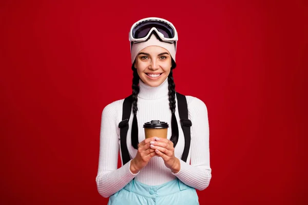 若い陽気な笑顔の正の美しい女の子のスキーヤーのお茶を飲む冬の休暇中に孤立した赤の色の背景 — ストック写真
