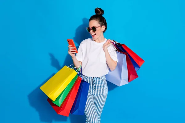 Θετική χαρούμενο κορίτσι εμπορικό κέντρο πελάτη χρήση smartphone διαβάσει κοινωνικό δίκτυο off-sales κοινοποίηση κρατήσει τσάντες φορούν λευκό t-shirt ριγέ τζιν απομονωμένο φωτεινό λαμπερό φόντο χρώμα — Φωτογραφία Αρχείου