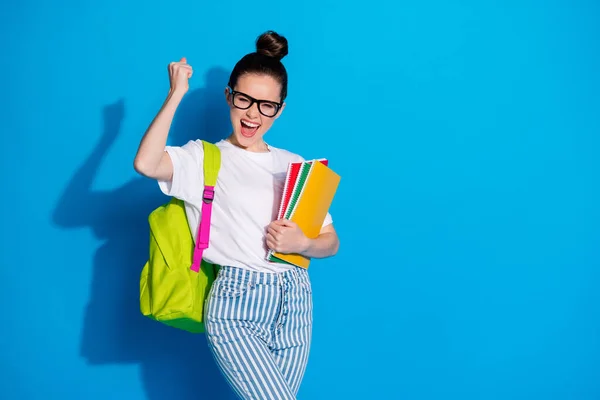 Porträtt av galen extatisk flicka hålla många böcker copybooks ryggsäck njuta extra föreläsning kurser vinna lotteri höja nävar skrika ja bära vit denim isolerad ljus glans färg bakgrund — Stockfoto