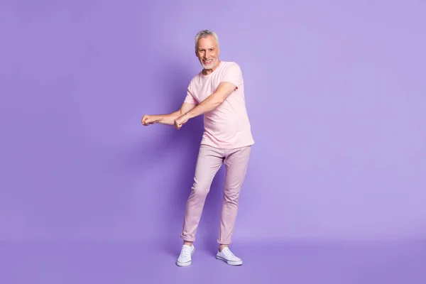 Pleine longueur photo de pensionné grand-père danse poings porter rose t-shirt pantalon baskets isolé violet couleur fond — Photo