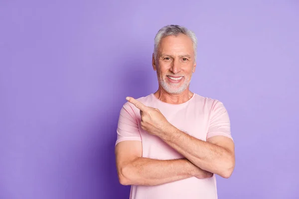 Foto des pensionierten Opas zeigen Zeigefinger leeren Raum tragen rosa T-Shirt isoliert lila Farbe Hintergrund — Stockfoto