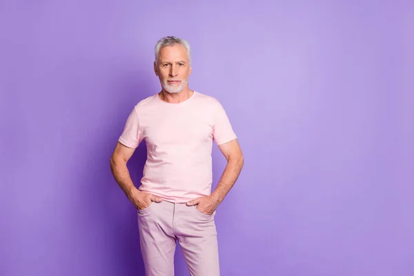 Фото самоуверенного дедушки карманы рук выглядят камера носить розовые брюки футболки изолированный фиолетовый цвет фона — стоковое фото