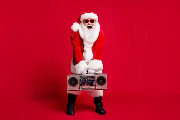 Full length photo of pensioner old man grey beard hold boombox open mouth wear santa x-mas costume gloves coat belt sunglass headwear black boots isolated red color background — Stock Photo, Image
