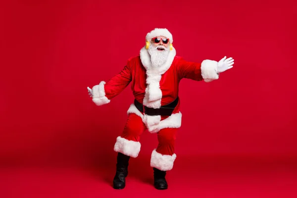 Comprimento total x-mas foto do pensionista homem velho barba branca avião dança ano novo festa desgaste santa traje luvas casaco cinto óculos de sol headwear botas pretas isolado fundo cor vermelha — Fotografia de Stock