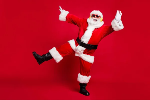 Full length foto di pensionato vecchio uomo grigio barba mani fino bocca aperta entartainer indossare Santa costume x-mas cappotto cintura occhiali da sole copricapi cuffie nero stivali isolato colore rosso sfondo — Foto Stock