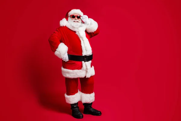 Yakışıklı, neşeli, sakallı Noel Baba 'nın tam boy vücut ölçüsü. Dokunaklı poz veriyor. Noel zamanı indirimli, parlak, parlak, parlak, kırmızı arka plan. — Stok fotoğraf