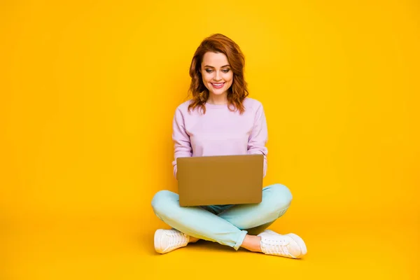 Full-Size-Foto von positiven fröhlichen Frau sitzen Beine gekreuzt verwenden Computer lesen Nachrichten online kommunizieren mit Kollegen Familie tragen Krickente Pullover isoliert über gelben Farbhintergrund — Stockfoto