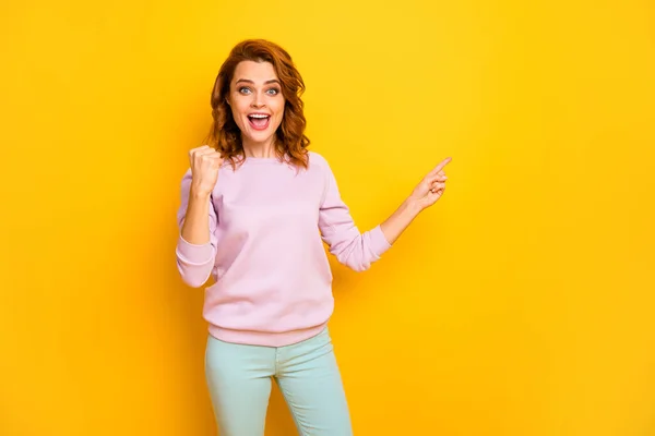 Photo of pretty lady indicate finger empty space propose novelty sale prices raise fist celebrate black friday beginning wear pink pullover green pants isolated yellow color background — Stock Photo, Image