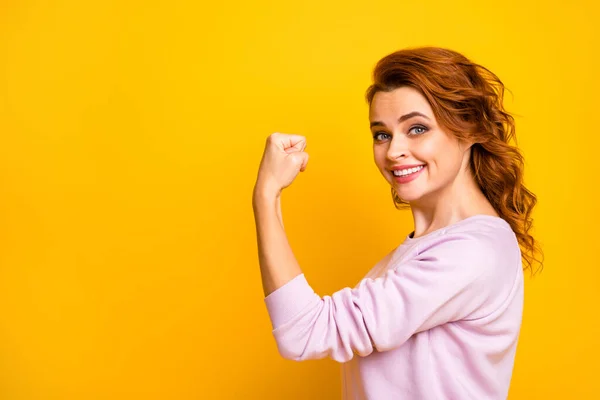 Profile photo of confident cheerful wavy lady raise fist up showing strong biceps muscle toothy smiling wear casual pink pullover isolated yellow color background — Stock Photo, Image