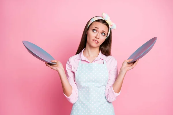 Ritratto di lei lei bella attraente piuttosto triste esitante stanco annoiato dai capelli castani cameriera tenendo in mano due piatti pensando fantasticando noia isolato su sfondo rosa pastello — Foto Stock