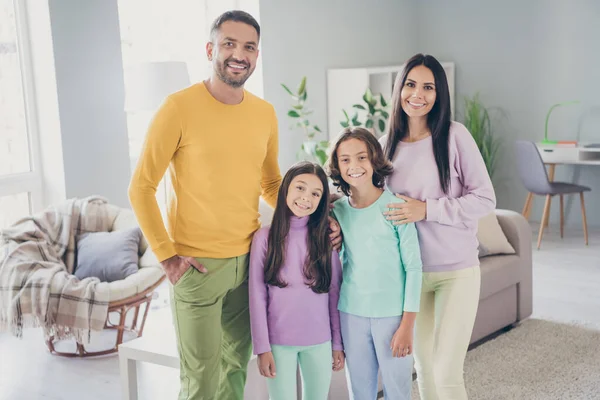 Φωτογραφία της πλήρους οικογένειας τέσσερα άτομα που συγκεντρώνει δύο μικρά παιδιά ματιά κάμερα φορούν πολύχρωμο παντελόνι πουλόβερ στο σαλόνι σε εσωτερικούς χώρους — Φωτογραφία Αρχείου