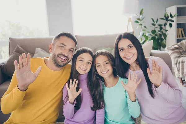 Foto einer vierköpfigen Familie, zwei kleine Kinder winken mit der Handkamera und tragen einen bunten Pullover im Wohnzimmer — Stockfoto