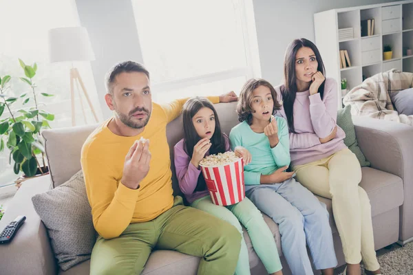 Foto de família cheia quatro pessoas sentar sofá comer pipoca assistir filme assustado usar pulôver colorido na sala de estar dentro de casa — Fotografia de Stock