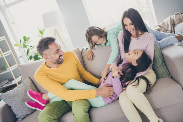 Fotografie plné velké rodiny čtyři členové dcera ležel kolena vydržet lechtání oblečení barevné svetr kalhoty v obývacím pokoji uvnitř — Stock fotografie