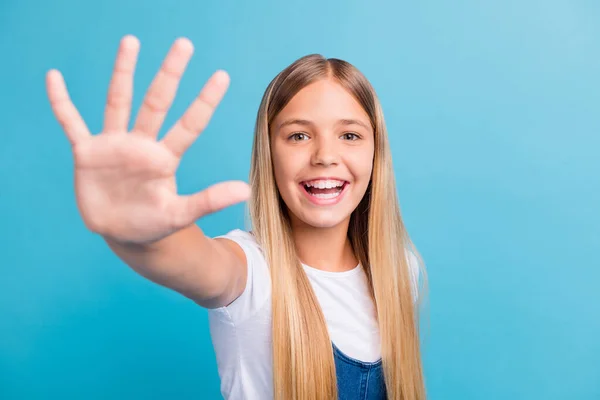 Foto av positiv liten blond flicka viftande hand i kameran bära vit t-shirt isolerad över blå färg bakgrund — Stockfoto