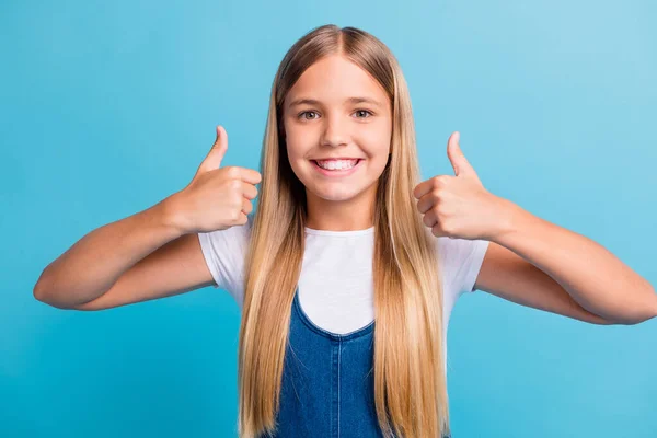 Foto van mooie vrolijke tiener blond lang haar meisje duimen omhoog dragen witte t-shirt geïsoleerd over pastel blauwe kleur achtergrond — Stockfoto