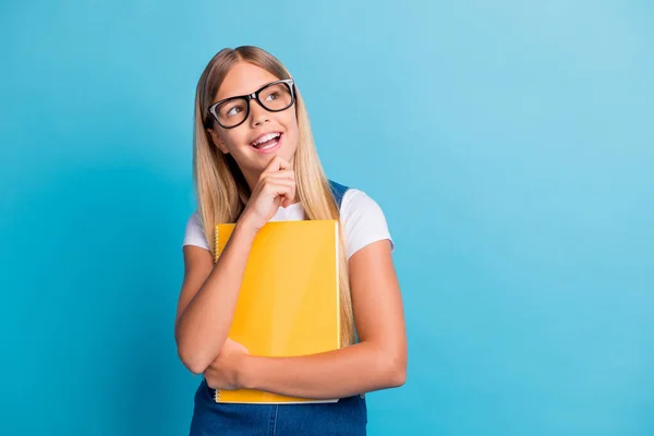 Foto de menina aluna alegre bonito pensando olhando espaço vazio desgaste óculos segurar livro isolado no fundo cor azul pastel — Fotografia de Stock