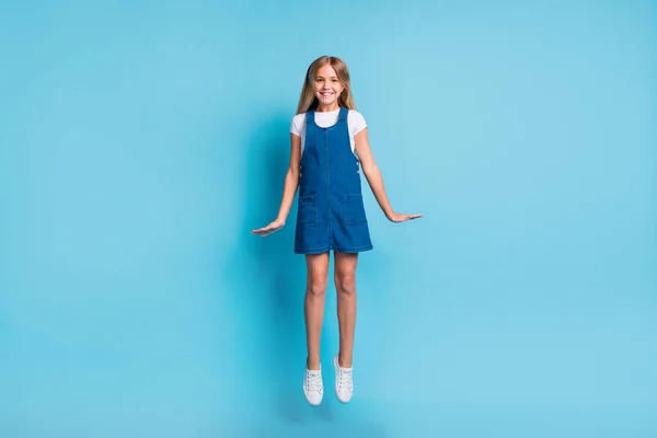 Foto de tamaño completo de niña rubia positiva loca saltando desgaste blanco camiseta zapatos de vestir aislados en fondo de color azul pastel — Foto de Stock